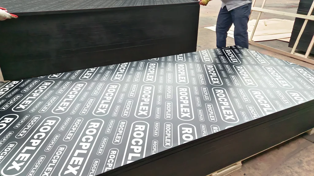 Large film faced plywood sheet ready for concrete formwork use Large size ROCPLEX film faced plywood panels for concrete formwork being handled in factory